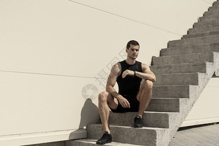 强健的运动员坐在上楼梯的底部图片