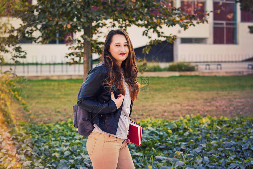 上学的年轻女子背着包和书本女孩走路的图片