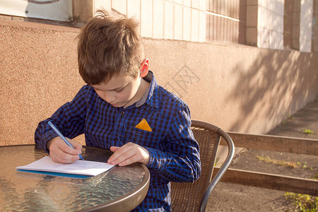 男孩在户外做家庭作业男孩用纸画或写信图片
