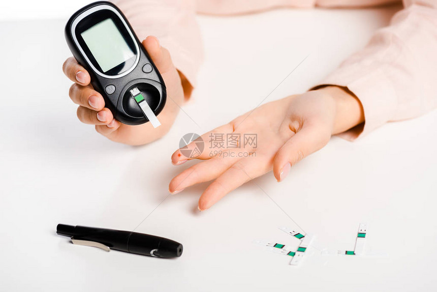 用白色糖尿病概念分离的血糖仪测量血液中葡萄糖水平的图片