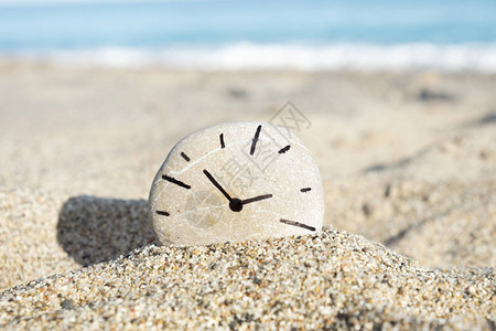 由我画的圆石和时钟在沙滩上的沙子上在图片