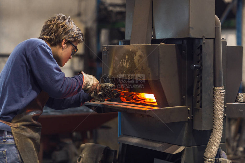 在一个金属加工车间工作的年轻木匠当他制造一个直立物体时图片