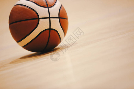木制球场地板上的篮球与背景中的模糊竞技场密切相关硬木篮球图片