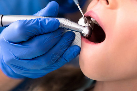 牙用手件和小孩牙齿一起工作的牙科医图片