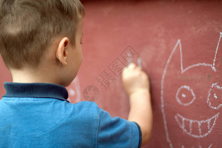 小男孩在墙上用粉笔画图片
