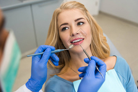 检查美丽女客户牙齿的牙科医生图片