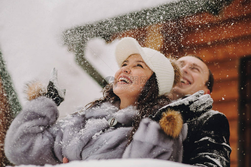 时尚的情侣在冬天雪山的背景下在木屋里玩雪幸福快乐的家庭在雪地里开心和微笑情感有趣图片