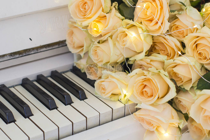 白色钢琴上带花环的桃玫瑰图片