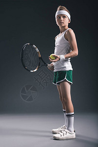 穿着运动服网球拍和球在深色背景上的沉思男孩图片
