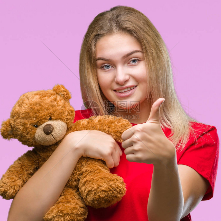 年轻的白人女在与世隔绝的背景下抱着可爱的泰迪熊图片
