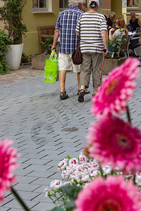 人们在德国南部春天的城市购物中心在粉红色的花朵后面购物图片