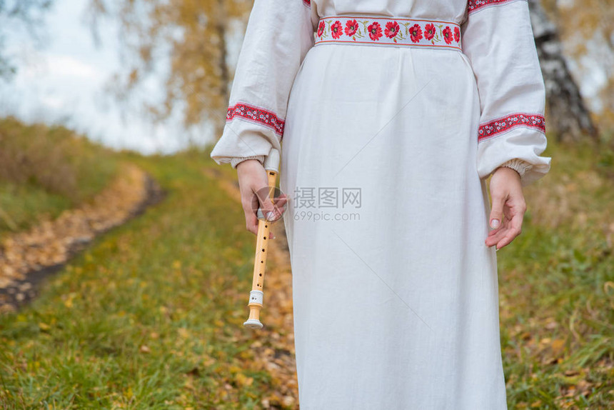 穿着斯拉夫礼服的女孩手里握着一只美丽的长笛在图片