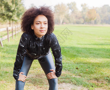 运动的女孩在跑到绿地上后放松图片