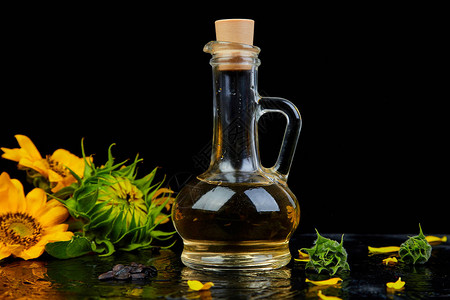 玻璃罐中的向日葵油向日葵种子和黑桌底的鲜花生物和有机产品概图片
