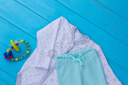 一套婴儿睡衣和豆袋蓝色木背景图片