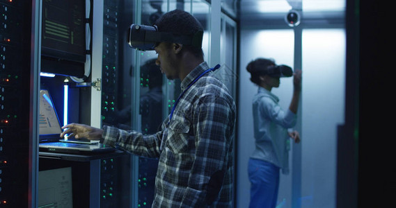 非洲裔美国同事在服务器机房数据中心使用硬件时戴着图片