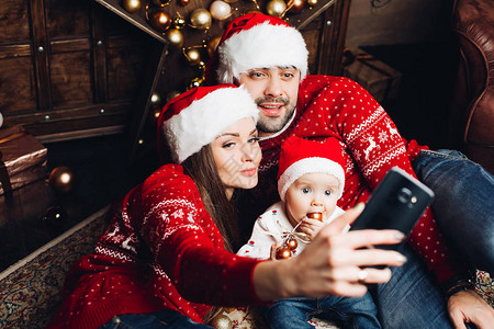 穿着红色圣诞毛衣和圣诞帽子的美丽年轻家庭肖像图片