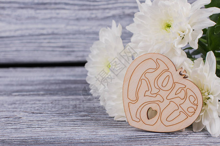 一束鲜花和木心情人节的白色菊花和雕刻的木制装饰品情图片