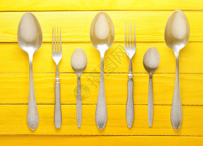 黄色木桌上的勺子和叉图片