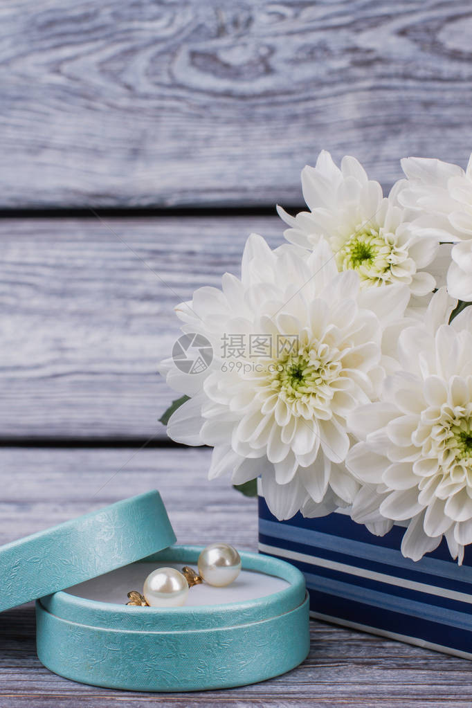 礼品盒中的珍珠耳环和白花美丽盛开的花朵和带金耳环的珠宝盒图片