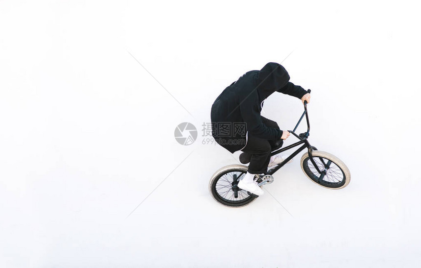 穿着深色衣服的Bmx骑自行车者骑在白色背景上在白色背景上孤立的bmx自行车上的自行车骑手图片