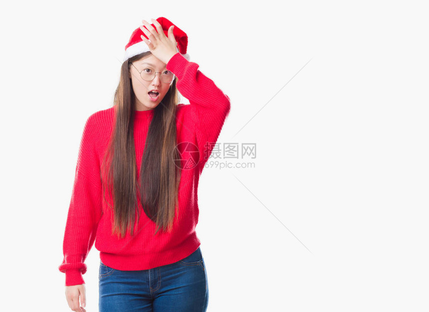 身穿圣诞帽的年轻女因错误而惊讶地用手捂着头图片