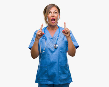 身处孤立背景的中年高级护士女医生惊讶地仰望并用手指和举起的手指着图片