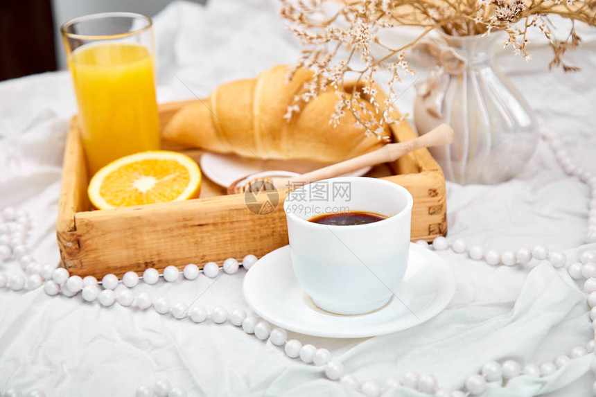 早上好白色床单上的欧陆式早餐一杯咖啡橙汁羊角面包木托盘上的果酱顶视图平躺复制空间图片