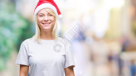 穿着圣诞帽的年轻金发美女与世隔绝的背景面带快乐和凉爽的笑图片