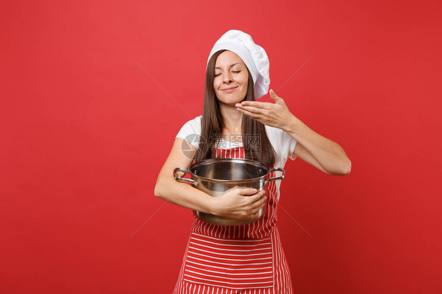 家庭主妇女厨师或面包师穿着条纹围裙白色t恤无边帽厨师帽隔离在红墙背景美丽的管家女人拿着空置的陶器罐模拟图片