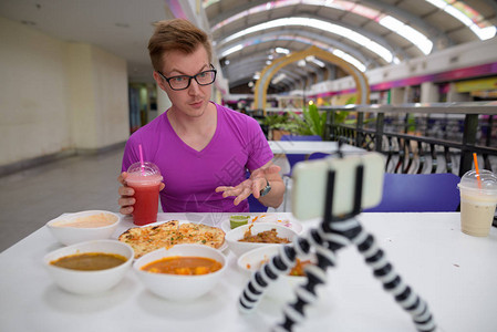 在曼谷市餐厅享受印度美食的年轻英俊旅游男子的肖像图片