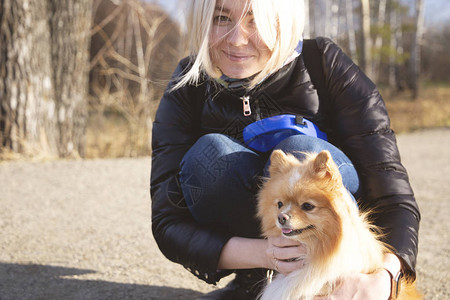 金发女孩与她的狗宠物pomeranianspitzpom在图片