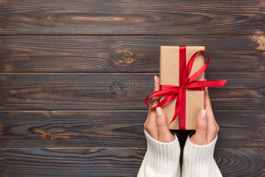女人的手用红丝带用纸包着情人节或其他手工制作的礼物图片