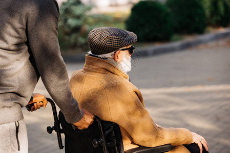 在街上骑着轮椅和护士的老年残疾男子在轮椅上被图片