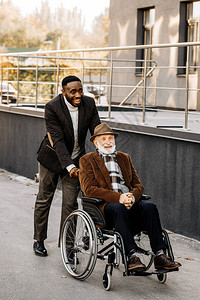 坐在轮椅上快乐的老年残疾人和在街上骑车图片