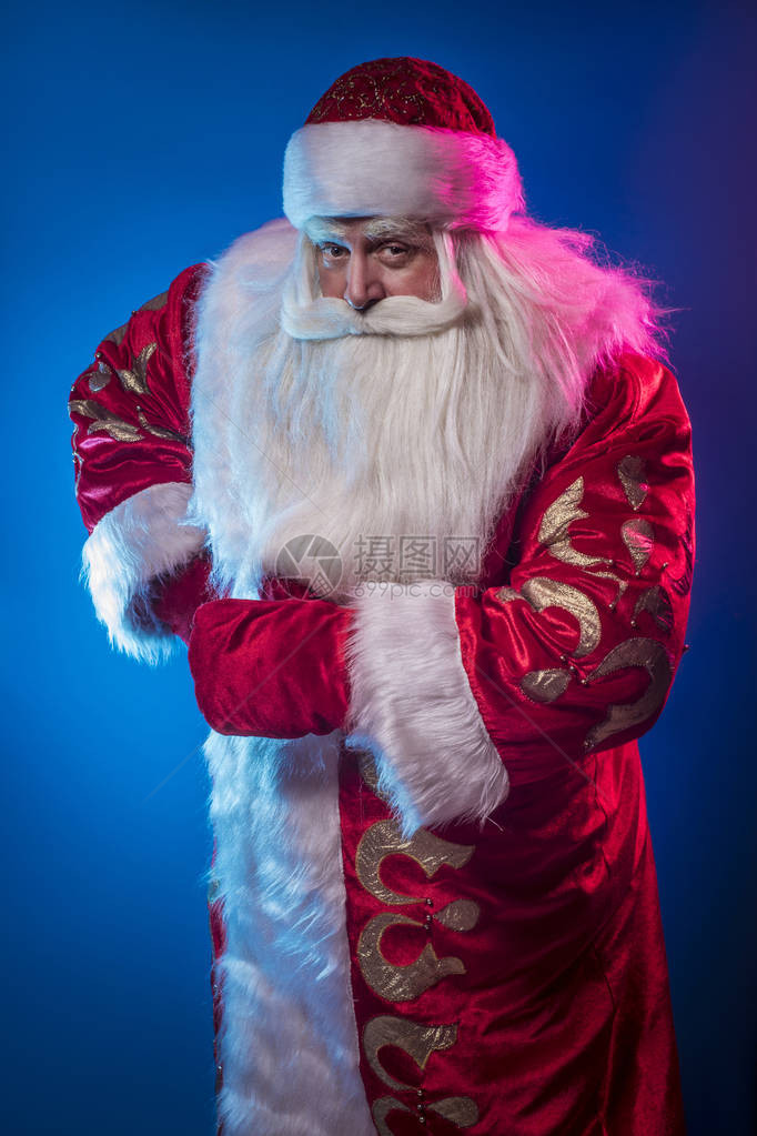 圣诞老人在蓝色和黑暗的背景下祝贺他这图片