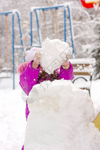 小女孩在冬日户外堆雪人图片