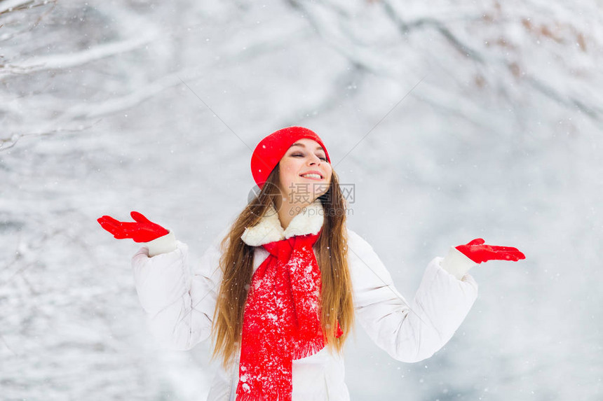 一个漂亮女孩闭上眼睛手掌举高享受冬季公园的风景图片