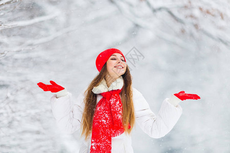 一个漂亮女孩闭上眼睛手掌举高享受冬季公园的风景图片