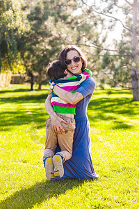 男孩正在拥抱他的母亲女人和她的儿子在公园里散步宝和妈玩得很开心图片