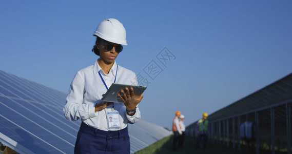 一名女电工在光伏太阳能电池板长行之间打平板上的女图片