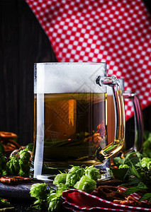 浅德国啤酒倒入大杯子新鲜的绿花和碗图片