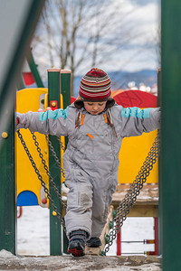小男孩在寒冬从户外操场的木桥图片