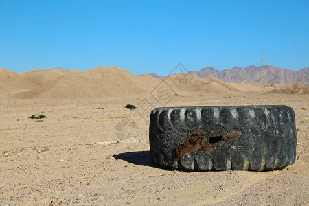沙漠中的旧黑色轮胎和其他垃圾图片