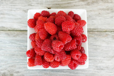 白色盘子上新鲜成熟的草莓在木制桌图片
