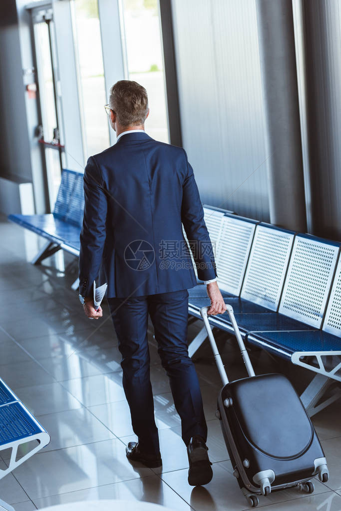背着旅行袋走在机场的商人的背影图片