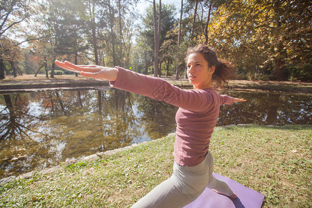 年轻女子在湖边公园的垫子上做瑜伽练习在美图片