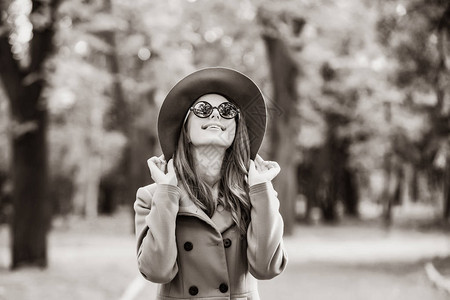 在秋天公园的太阳镜和帽子中女孩穿着太图片