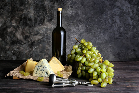 木桌上的一瓶酒配奶酪和成熟的葡萄图片