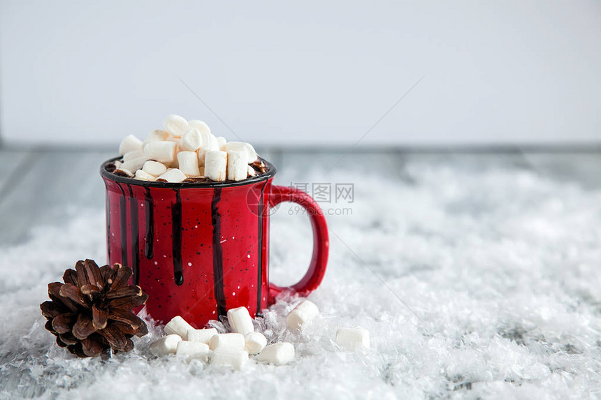 含棉花糖的热饮和雪覆盖木制背景图片